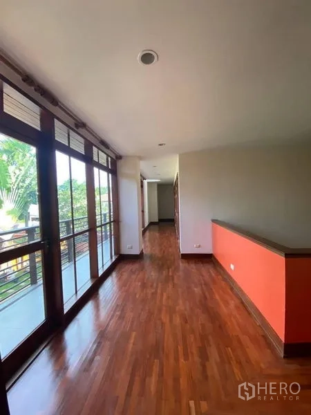 Detached House for rent in Suan Luang, Bangkok - Upstairs hallway with floor‑to‑ceiling windows, wood flooring and access to a balcony.