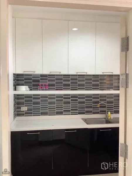 联排别墅 出租或出售在Wang Thonglang, Bangkok - 独立小厨房，白色吊柜、黑色地柜、灰色瓷砖防溅板与不锈钢水槽。