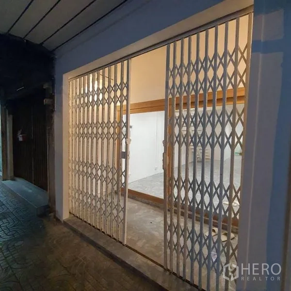 Shophouse for rent or sale in Khlong Toei, Bangkok - Street-facing frontage with sliding metal security gate at night.