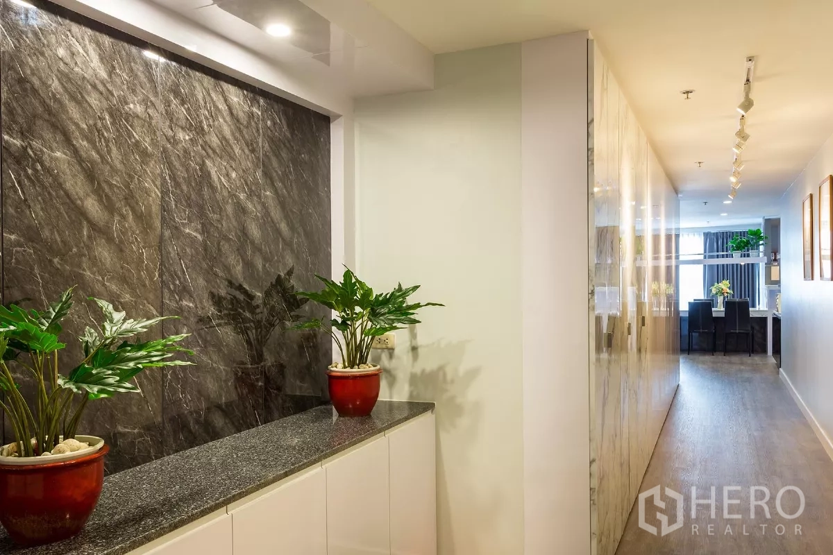 Condominium for rent or sale in Watthana, Bangkok - Condo corridor featuring a dark stone wall and potted plants.