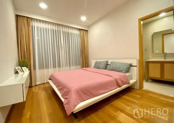 公寓 出租在Khlong Toei, Bangkok - 明亮卧室，粉色被套、木地板、大窗，并带套内卫浴。