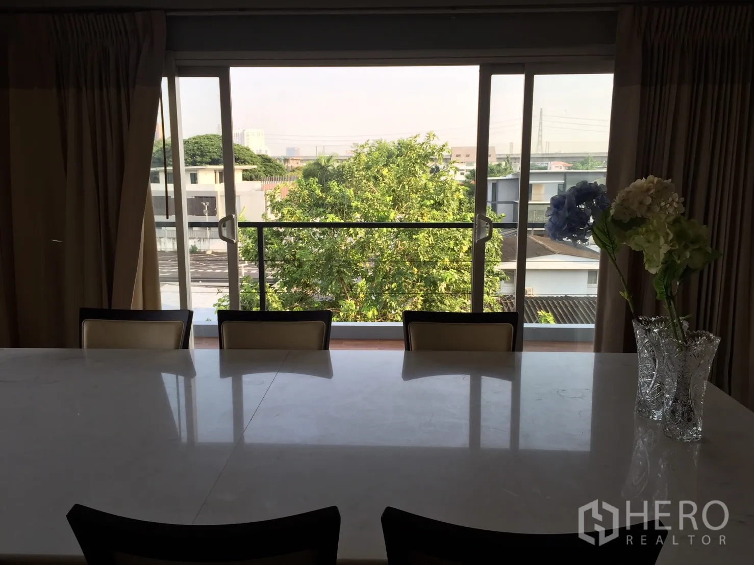 带办公室的家 出租或出售在Suan Luang, Bangkok - 餐区配大理石餐桌，对向推拉玻璃门与阳台绿景。