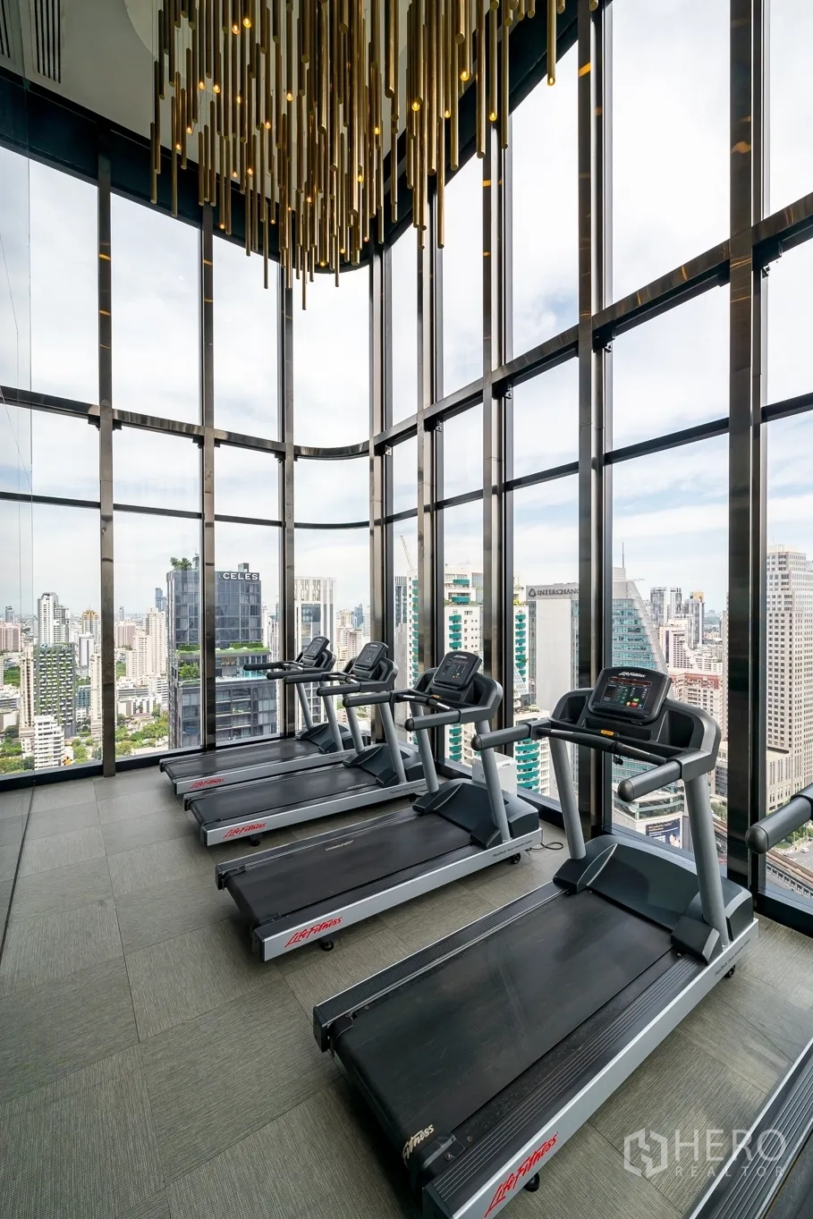 Condominium for rent in Watthana, Bangkok - Cardio room with treadmills under sculptural lighting and city views.