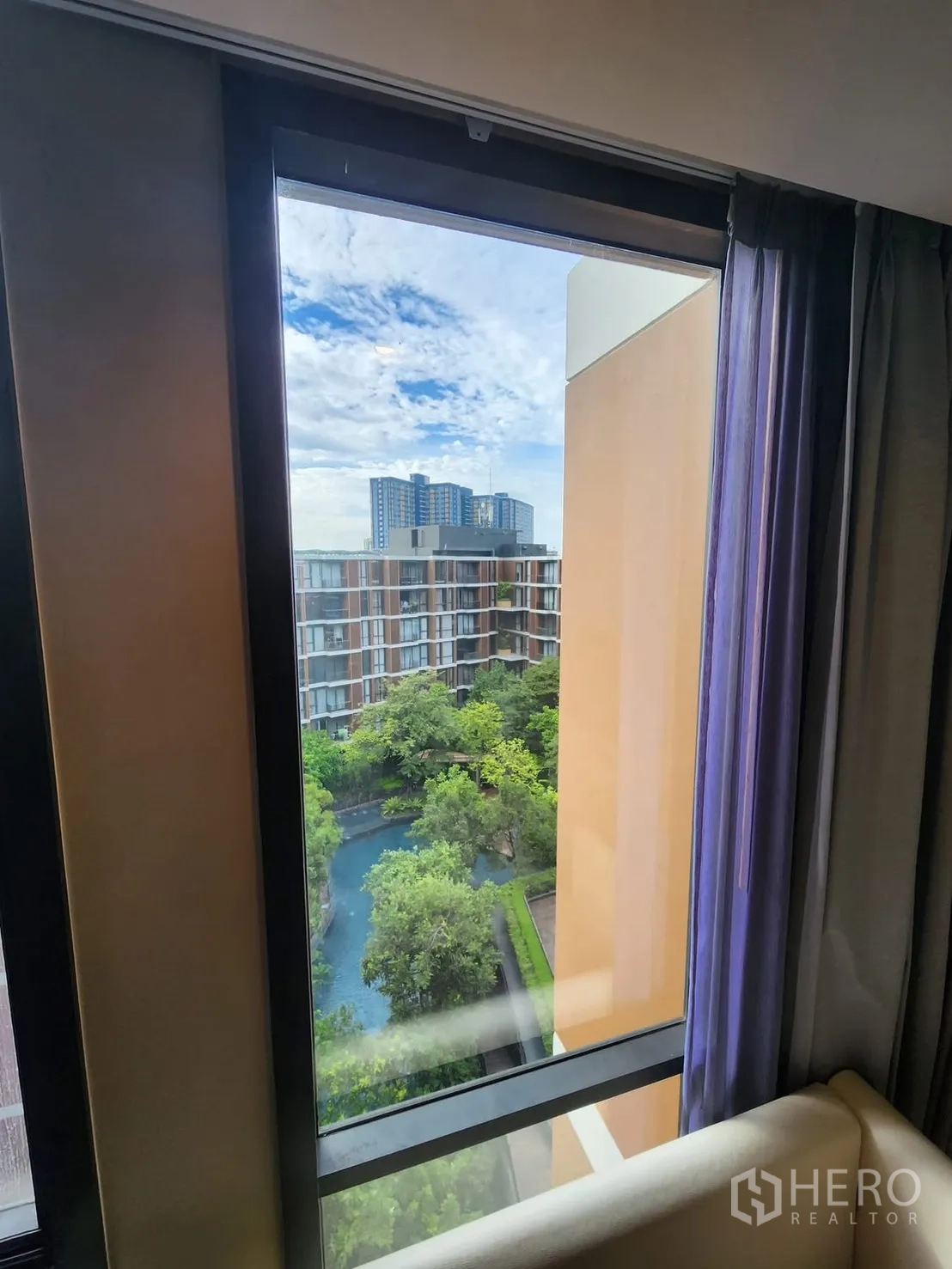 公寓 for rent in Watthana, Bangkok - 卧室观景窗框出花园与弯曲泳池的景致。