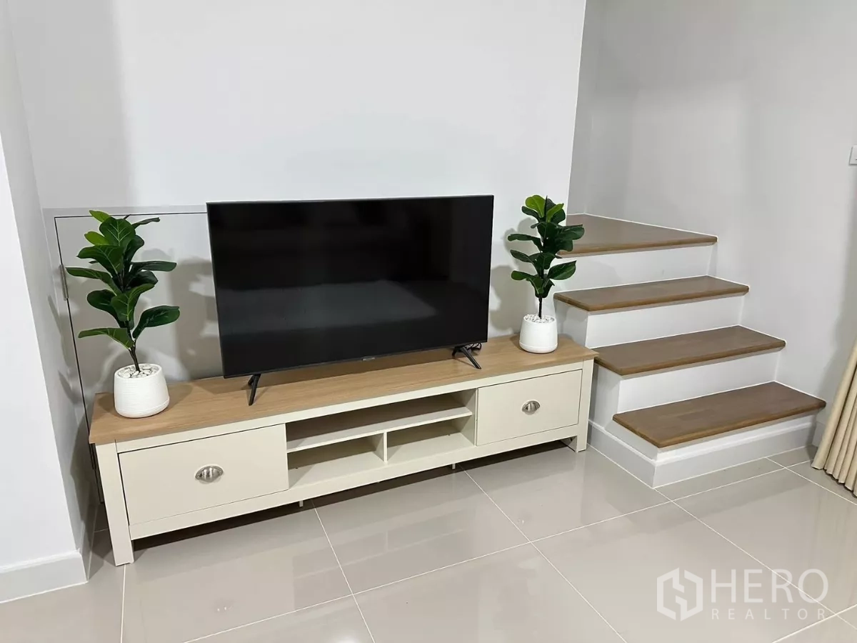 Townhouse for rent in Bang Phli, Samut Prakan - TV cabinet and staircase corner decorated with potted plants.