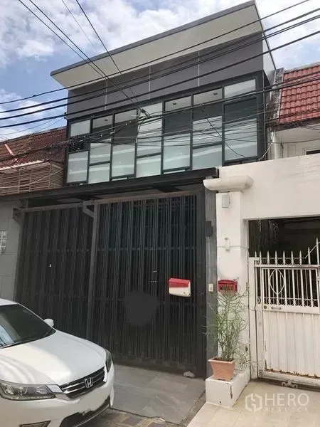 Home Office for rent in Khlong Toei, Bangkok - Modern two-storey home office exterior in Khlong Toei with full-width glass windows, tall sliding metal gate and a small driveway.