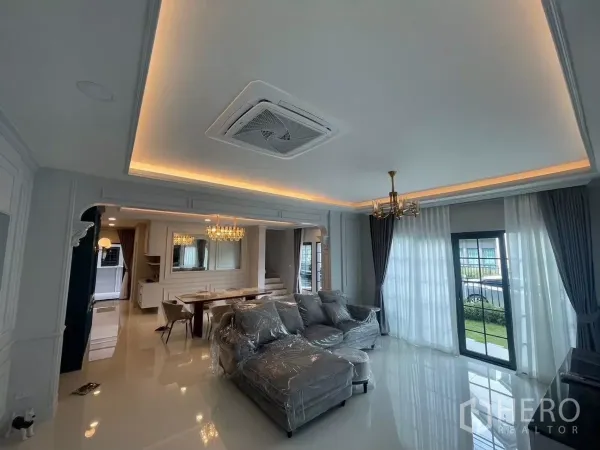 บ้าน ให้เช่าในBang Phli, Samut Prakan - ห้องนั่งเล่นสวยหรู ฝ้าซ่อนไฟ แอร์ฝัง โซฟาสีเทา และผ้าม่านโปร่งแสง