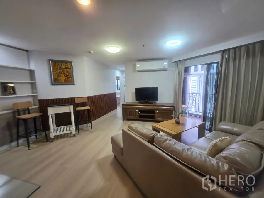 Condominium for rent in Huai Khwang, Bangkok - Living space facing the balcony with TV console, sofa, and curtains.
