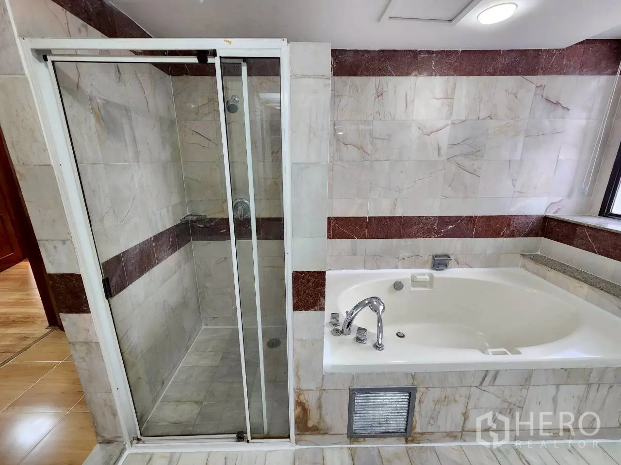 Condominium for rent in Khlong Toei, Bangkok - Marble-tiled bathroom with glass shower enclosure and separate soaking tub.