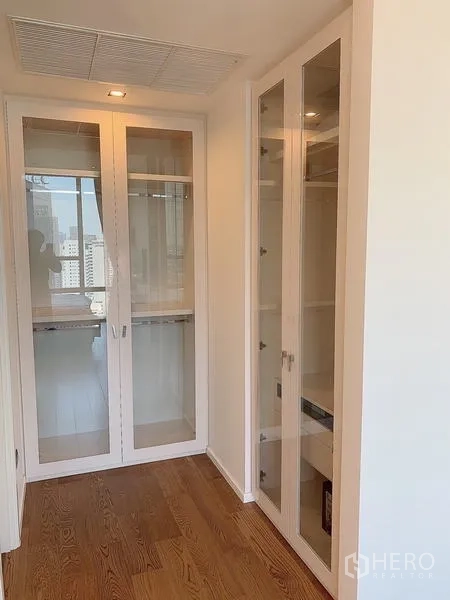 Condominium for sale - Compact walk-in storage with glass-front cabinets and a bright window.