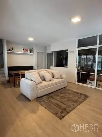 半独立式住宅 for rent in Prawet, Bangkok - 客厅配沙发与地毯，紧邻用餐角与木纹地面。