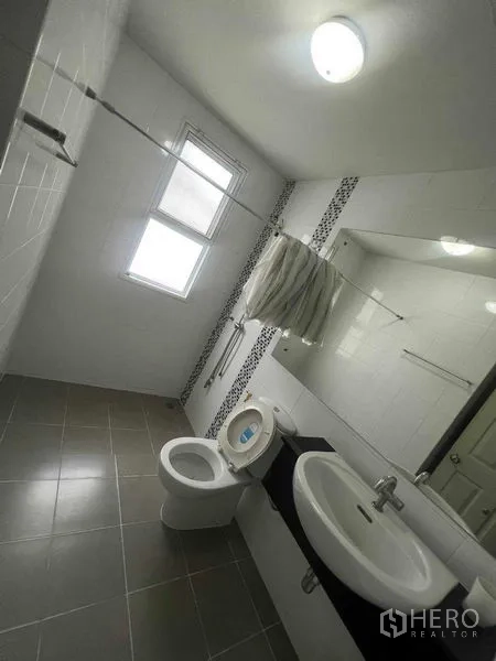 Townhouse for rent in Bueng Kum, Bangkok - Bright bathroom with long mirror, window and tiled floor.
