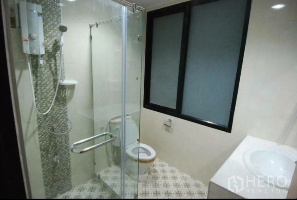 Home Office for rent in Lat Phrao, Bangkok - Modern bathroom with glass-enclosed shower, water heater and patterned floor tiles.