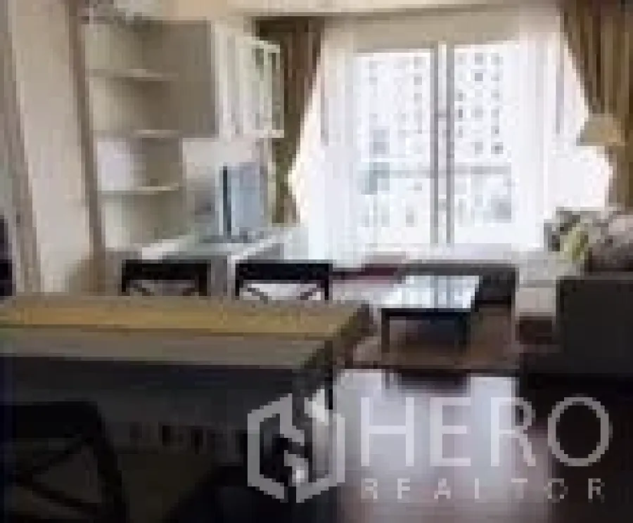 Condominium for rent in Watthana, Bangkok - Living area angle showing TV stand, dining set and large windows to the balcony.