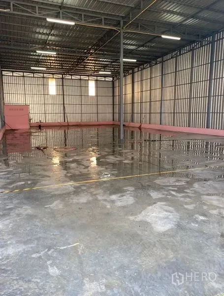 Warehouse for rent in Bueng Kum, Bangkok - Open-plan warehouse space showing central support column, ventilation windows and wet-cleaned concrete floor.