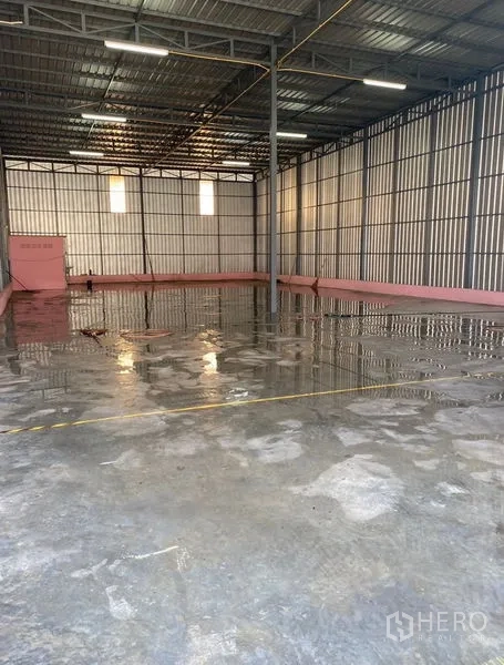 Warehouse for rent in Bueng Kum, Bangkok - Open-plan warehouse space showing central support column, ventilation windows and wet-cleaned concrete floor.