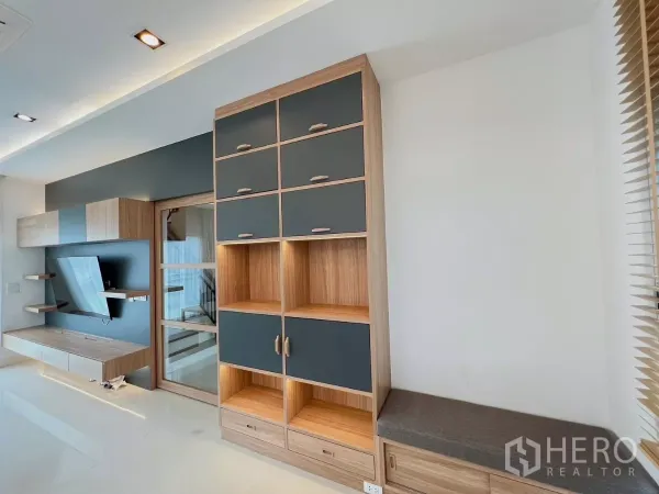 Detached House for rent or sale in Khlong Luang, Pathum Thani - Custom storage cabinet and glass sliding door beside the TV wall in open-plan space.