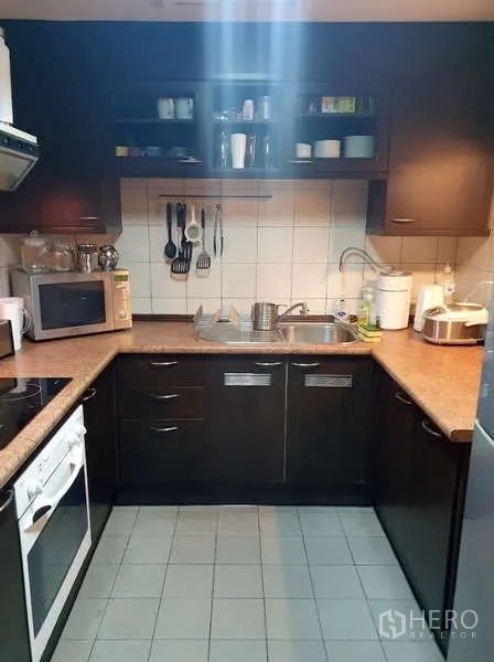 Condominium for sale in Pathum Wan, Bangkok - U-shaped kitchen with dark cabinets, oven and microwave