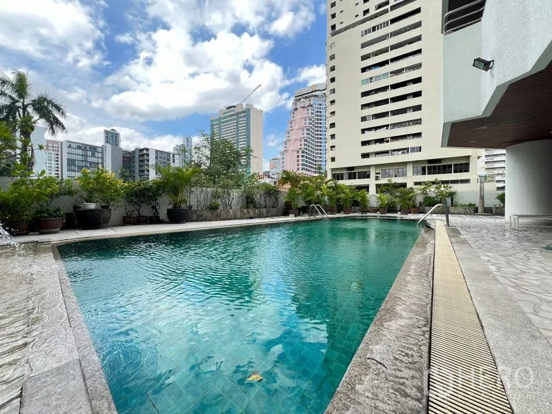 Condominium for rent or sale in Khlong Toei, Bangkok - Outdoor swimming pool surrounded by greenery and city buildings.