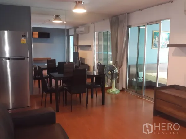คอนโด ให้เช่าในHuai Khwang, Bangkok - พื้นที่นั่งเล่นและรับประทานอาหารแบบเปิดโล่ง มีตู้เย็นสแตนเลส ชุดโต๊ะทานอาหาร พื้นไม้ และประตูกระจกสู่ห้องนอน