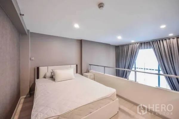 คอนโด ให้เช่าในSathon, Bangkok - ห้องนอนชั้นลอยรับแสงธรรมชาติจากหน้าต่างสูงจรดเพดาน พร้อมผ้าม่านสีเทาทึบแสง