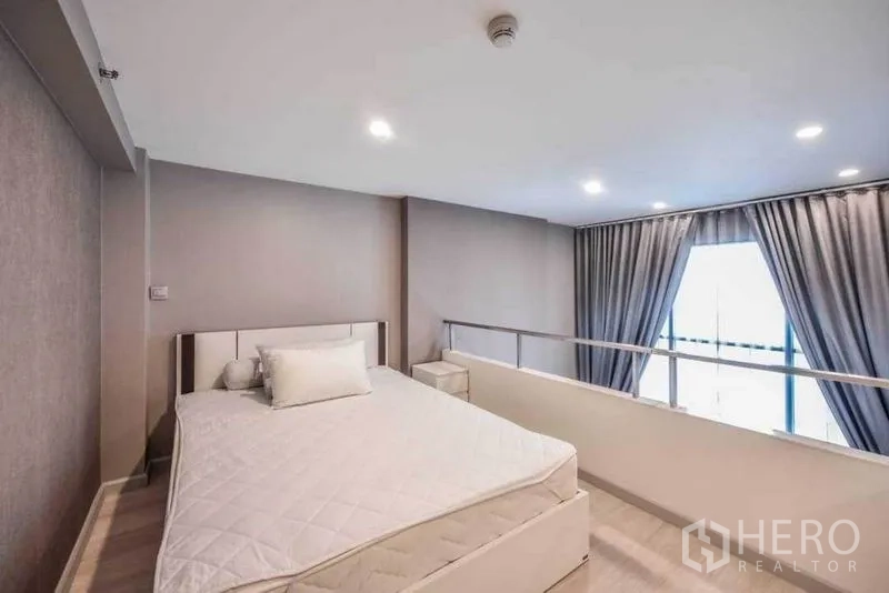 คอนโด ให้เช่าในSathon, Bangkok - ห้องนอนชั้นลอยรับแสงธรรมชาติจากหน้าต่างสูงจรดเพดาน พร้อมผ้าม่านสีเทาทึบแสง