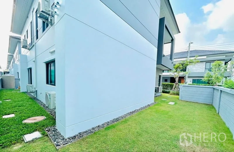 Detached House for rent in Bang Phli, Samut Prakan - Side yard with green lawn and privacy wall.