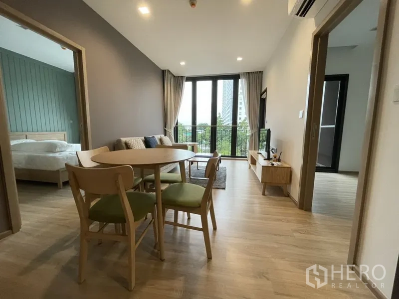 公寓 出租在Watthana, Bangkok - 餐桌位于两卧之间，大玻璃门通向阳台与花园景观。