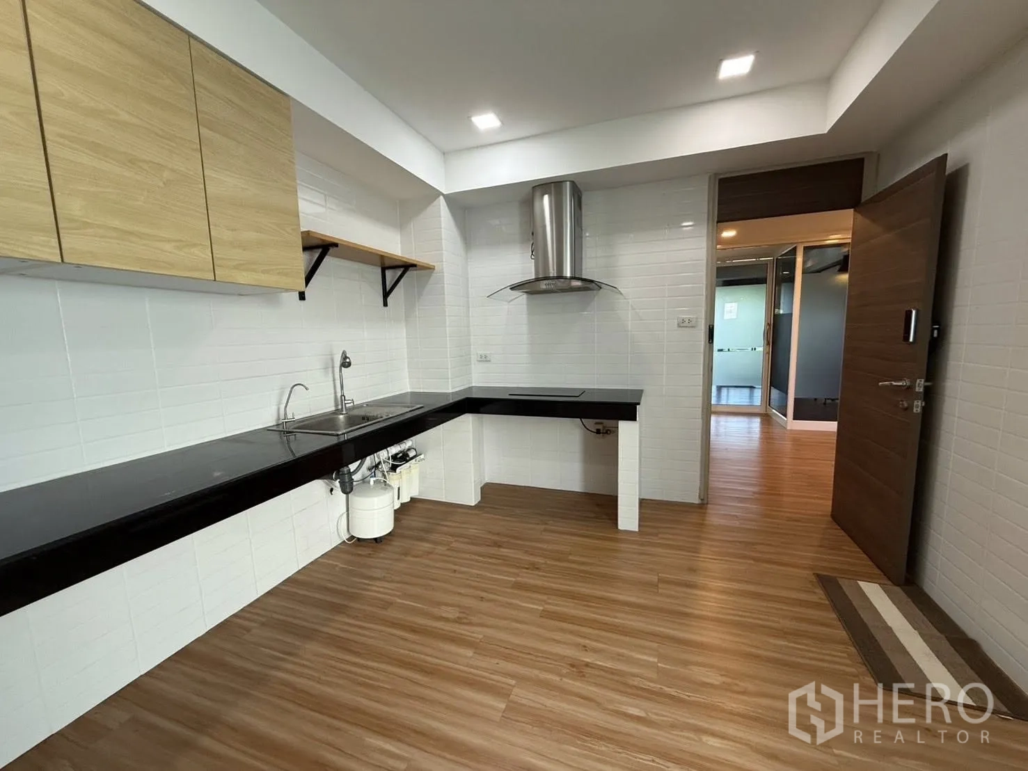 家庭办公室 for rent or sale in Yan Nawa, Bangkok - 厨房配白色瓷砖墙、黑色台面、水槽与吸油烟机。