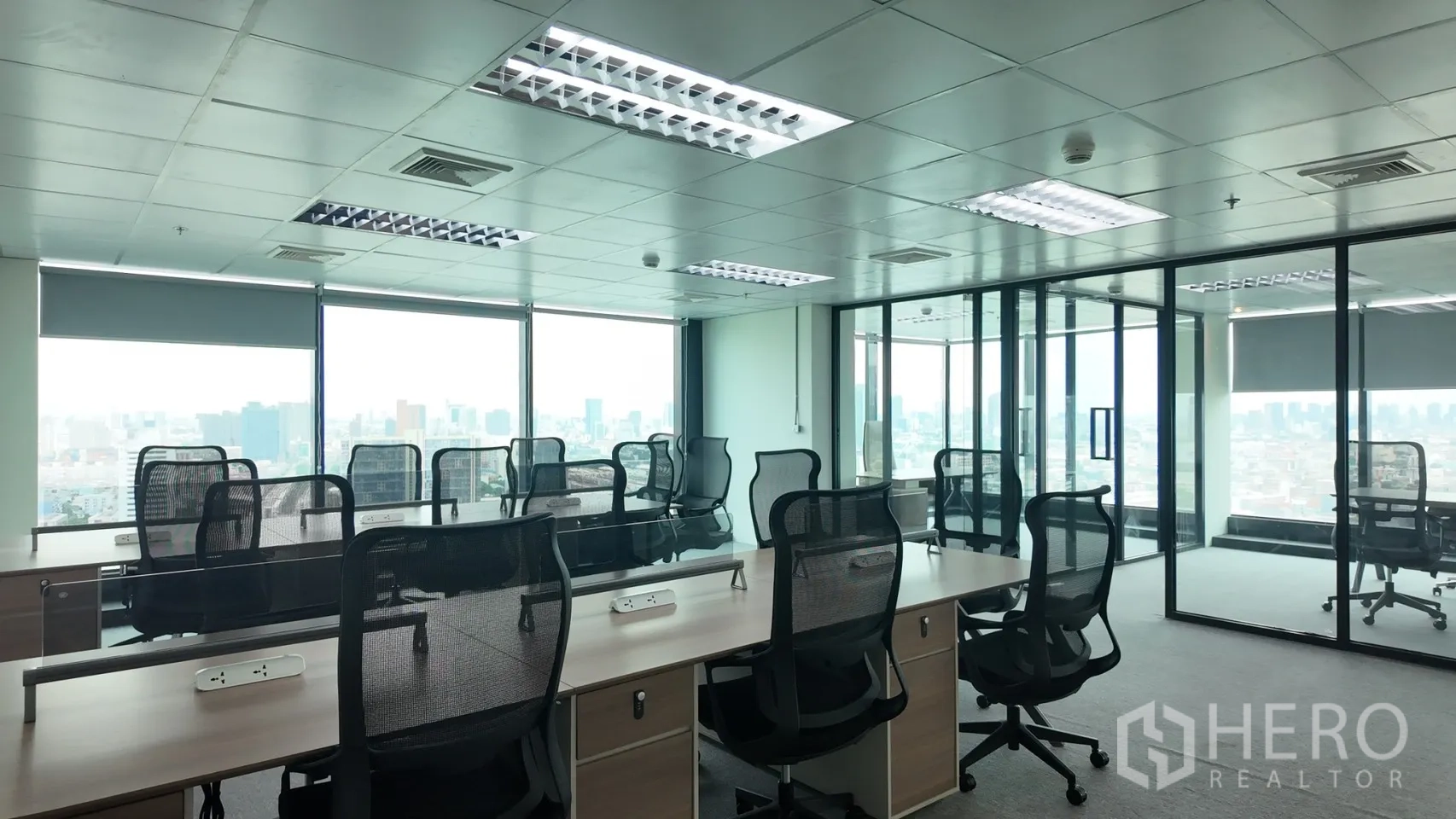 Office Space for rent in Din Daeng, Bangkok - Open-plan workspace with rows of desks, mesh chairs, and glass-partitioned rooms overlooking the city.