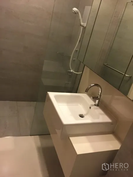 公寓 出租在Khlong Toei, Bangkok - 现代卫浴，玻璃淋浴间、大镜柜与白色台盆。