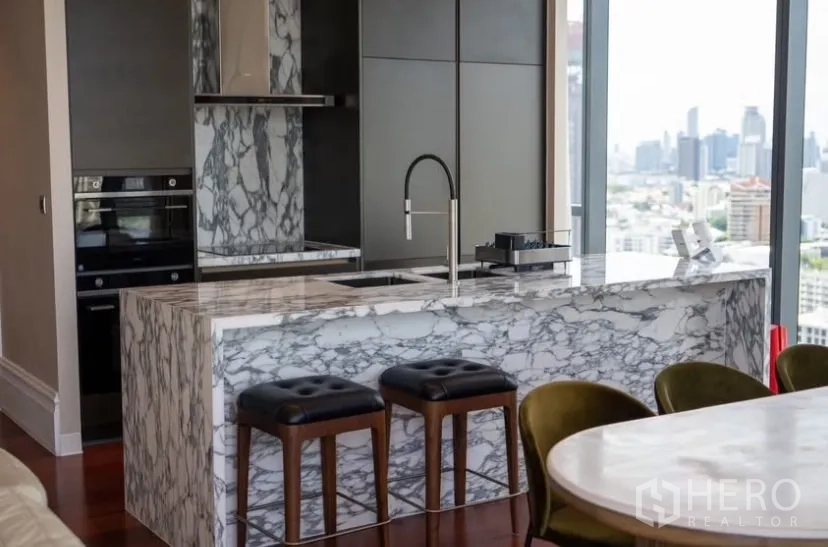 Condominium for rent or sale in Watthana, Bangkok - Close-up of marble breakfast island with sink and bar stools.