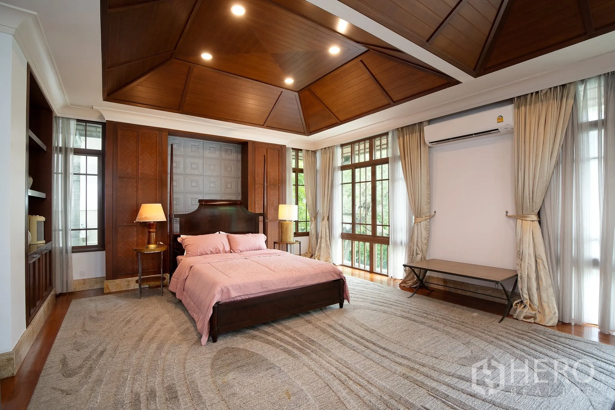 บ้านเดี่ยว for rent or sale in Watthana, Bangkok - ห้องนอนหลักกว้าง เพดานไม้เล่นระดับ หน้าต่างบานใหญ่ และเตียงผ้าปูสีชมพู