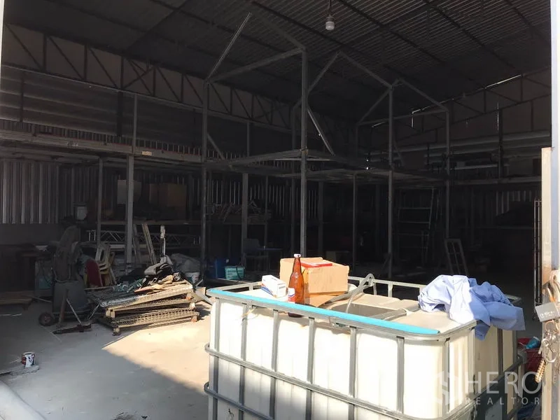 Warehouse for rent in Mueang Samut Prakan, Samut Prakan - Spacious warehouse interior with high steel truss roof, shelving frames and an open floor suitable for storage and loading.