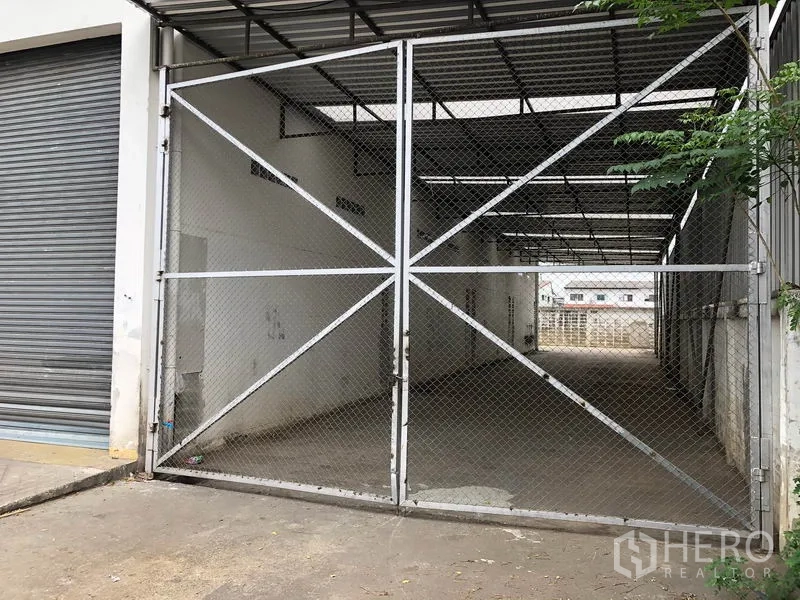 Factory for rent in Nonthaburi - Mesh double gate opening to a covered service lane beside the roller door.