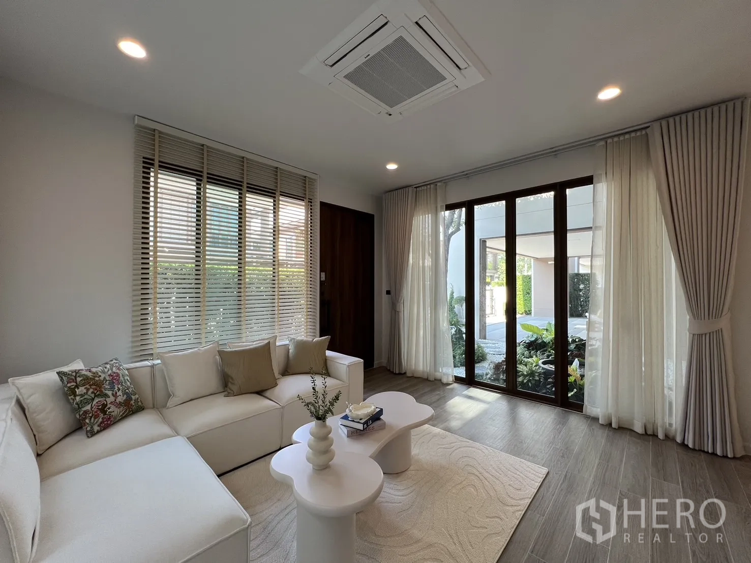 独立式住宅 出租或出售在Bang Kapi, Bangkok - 起居区面向露台门与花园，木纹地板与浅色地毯。
