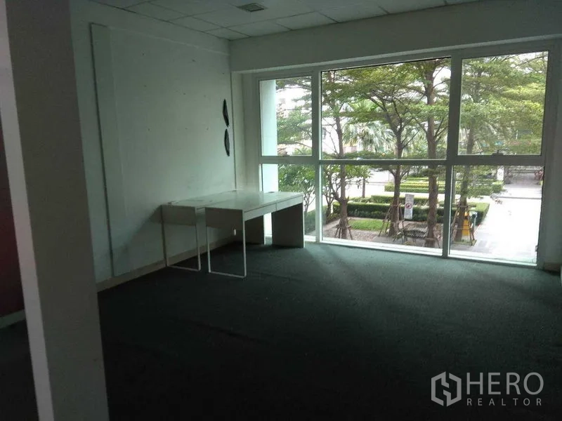 Retail Space for rent in Huai Khwang, Bangkok - Corner workspace with a large floor-to-ceiling window overlooking a green courtyard.
