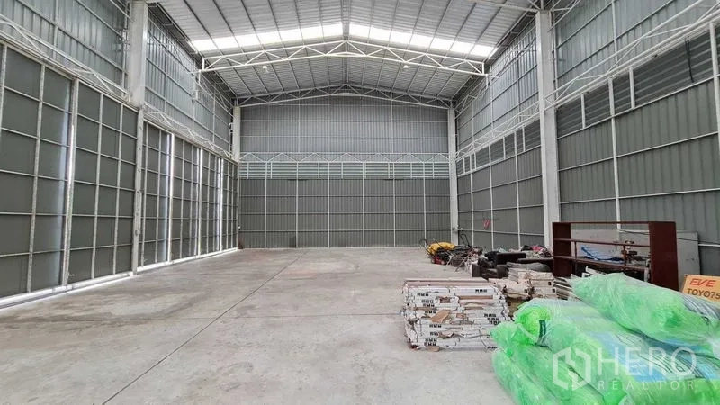 Warehouse for rent in Mueang Nonthaburi, Nonthaburi - High-ceiling warehouse interior with steel trusses, skylights and a durable concrete floor.