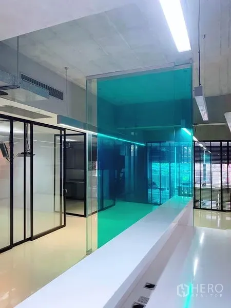 办公空间 出租在Phaya Thai, Bangkok - 现代办公室内景，蓝绿色玻璃会议室、黑框玻璃隔断、抛光地面与裸露天花。