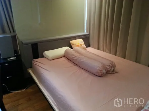 Condominium for rent or sale in Khlong Toei, Bangkok - Bedroom with pink bedding, bolster pillows, floor-to-ceiling curtains and wood flooring.