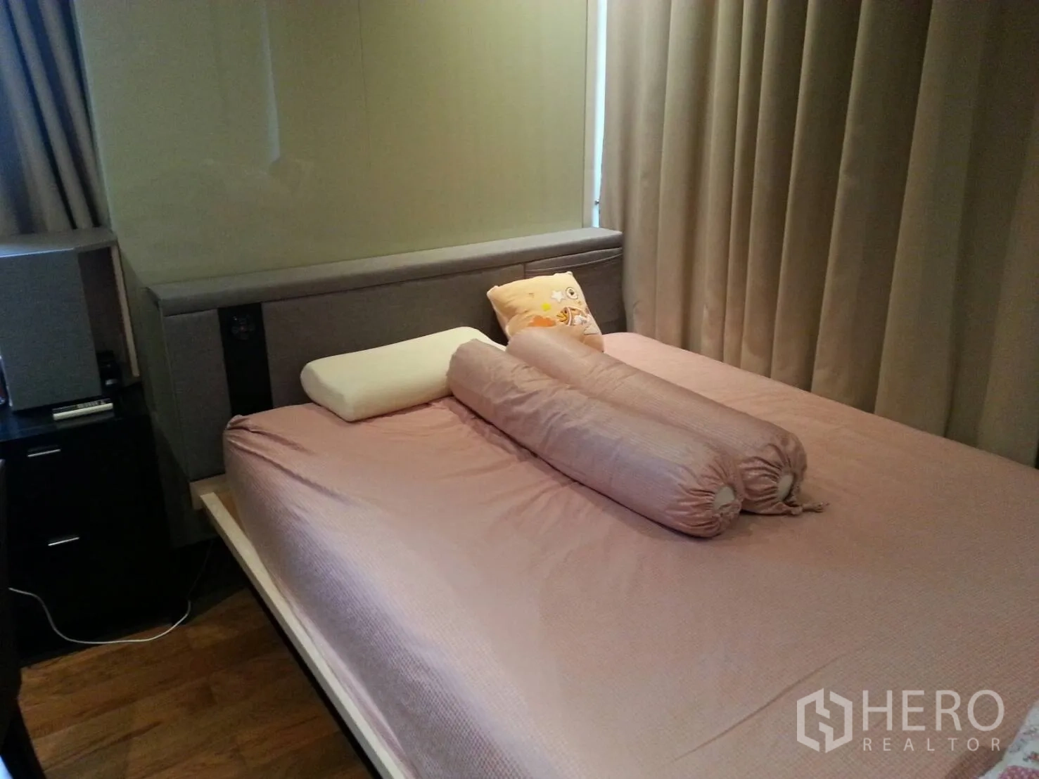 Condominium for rent or sale in Khlong Toei, Bangkok - Bedroom with pink bedding, bolster pillows, floor-to-ceiling curtains and wood flooring.