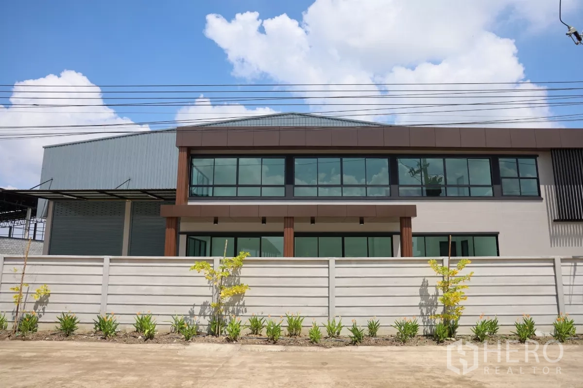 工厂 出租或出售在Bang Len, Nakhon Pathom - 工厂与两层办公楼的街景立面，设有围墙与整齐绿化带。