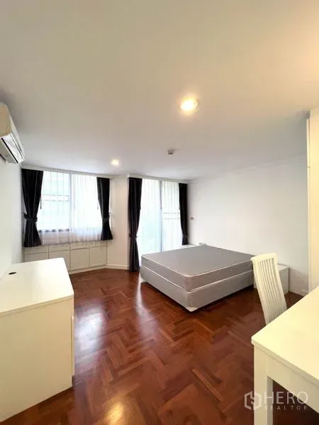 公寓 出租在Watthana, Bangkok - 卧室铺设拼花木地板，设大窗与深色窗帘、平台床与书桌。