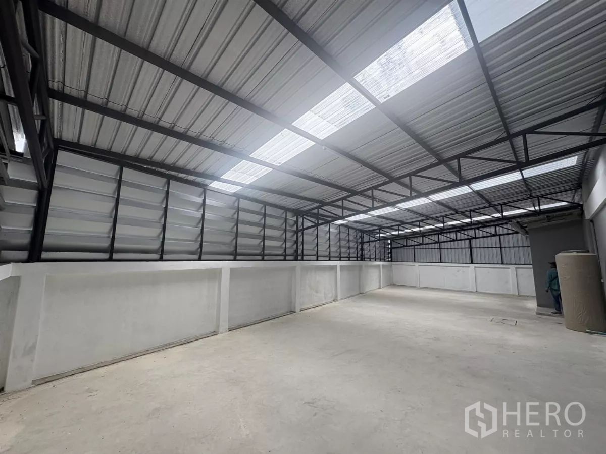 Factory for rent in Phra Samut Chedi, Samut Prakan - Covered mezzanine storage area with metal roof, ventilation louvers and translucent panels.