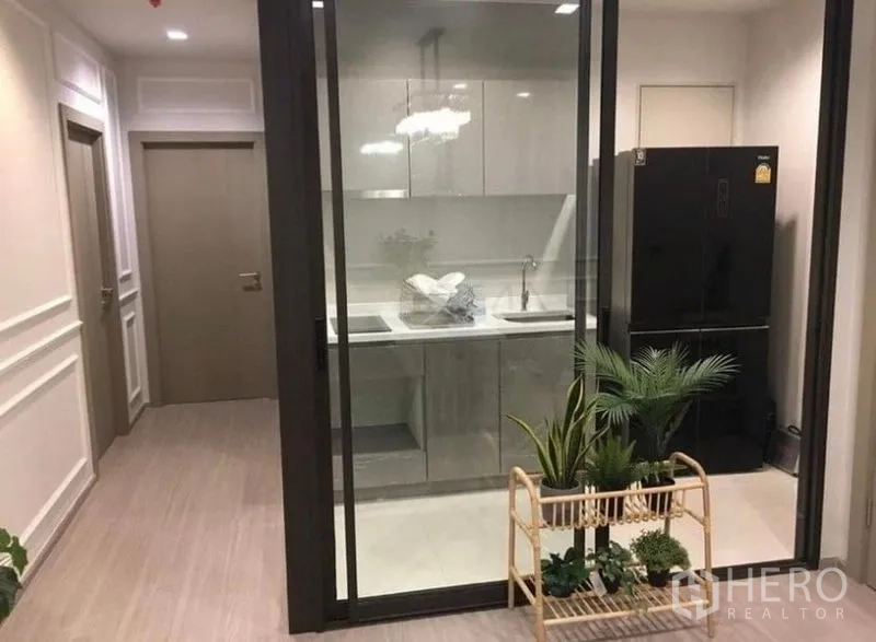 公寓 出租在Ratchathewi, Bangkok - 封闭式厨房，亮面橱柜、水槽与黑色冰箱。