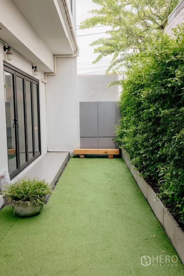 Detached House for rent or sale in Bang Phli, Samut Prakan - Narrow side garden with green hedge and bench along the wall.