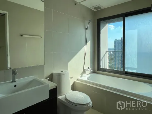 Condominium for rent in Khlong Toei, Bangkok - Bathroom with bathtub, shower and a window offering a city view.