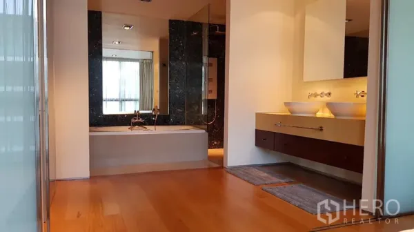 Condominium for rent in Khlong Toei, Bangkok - Spa-style master bathroom featuring a double vanity, soaking tub and separate glass shower with wood flooring.