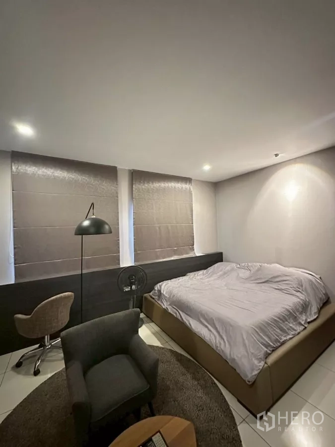 Detached House for sale in Bang Lamung, Chon Buri - Guest bedroom with king bed, lounge chair and soft lighting.