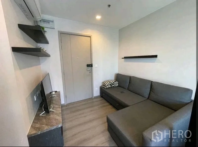 公寓 出租在Yan Nawa, Bangkok - 温馨起居角，灰色转角沙发、壁架与电视柜。